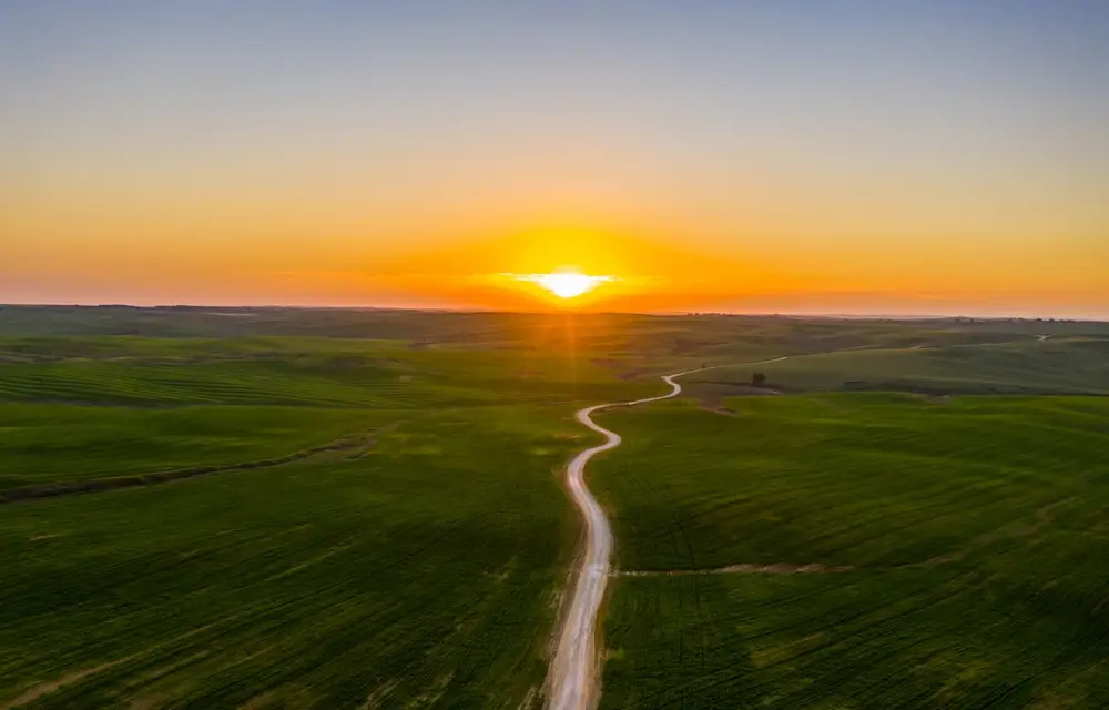 An open road running toward the horizon at sunrise